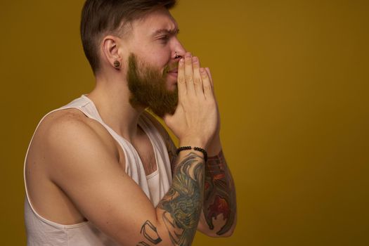 Cheerful bearded man in a white T-shirt with hooligan tattoos on his arms. High quality photo