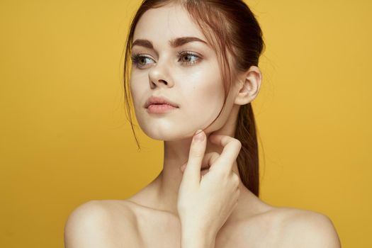 woman with bare shoulders clean skin hairstyle posing yellow background. High quality photo