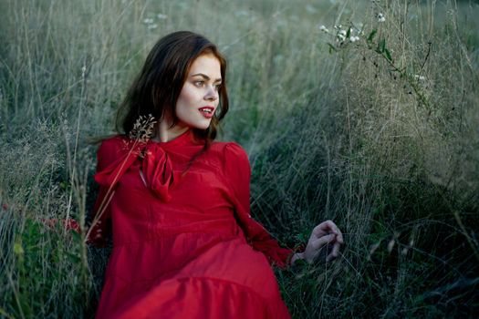 woman lies on the grass in a red dress landscape fashion. High quality photo