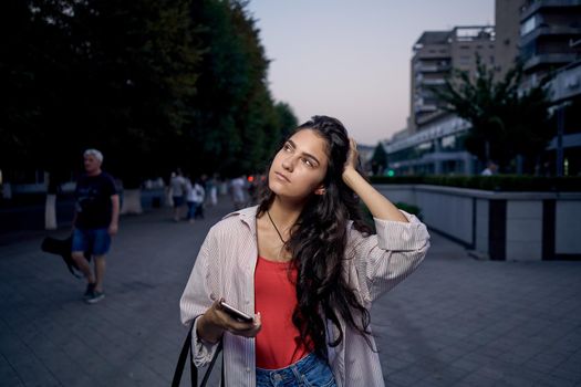 woman talking on the phone outdoors walking in the evening on the street. High quality photo
