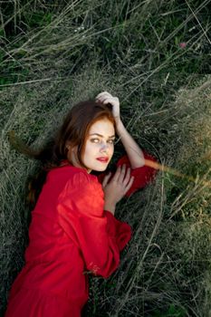 pretty woman in red dress lies on the grass posing top view. High quality photo