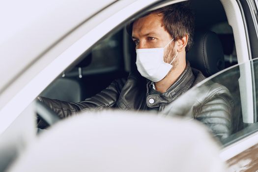 Young man driving car in medical mask, portrait