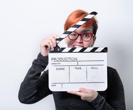 redhead woman on white background  holding movie clapper cinema concept