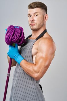 man in apron with mop in hand posing housework. High quality photo