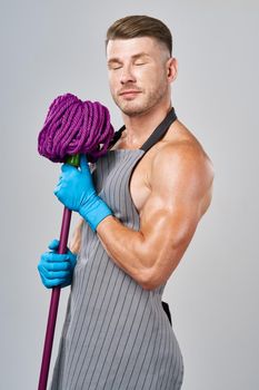 Muscled man in apron with mop posing cleaning. High quality photo