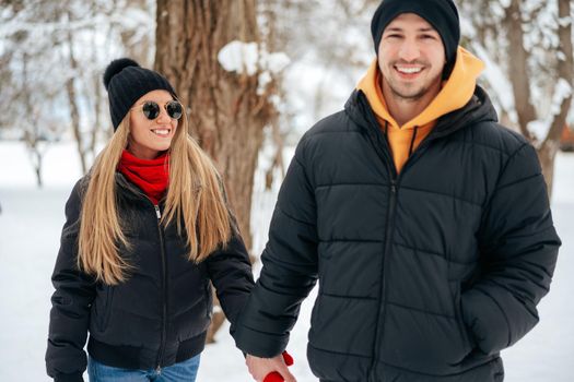 Happy couple hugging and smiling outdoors in snowy park close up