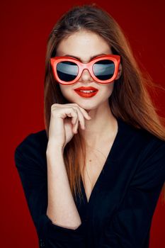 pretty woman wearing sunglasses fashion posing hairstyle red background. High quality photo