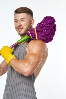 muscular man in a gray apron with a mop posing. High quality photo