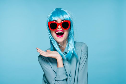 joyful woman purple wig fashion glasses hand gestures blue background. High quality photo