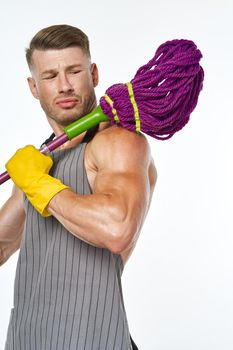 muscular man in a gray apron with a mop posing. High quality photo
