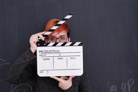 redhead woman on black chalkboard holding movie clapper cinema concept