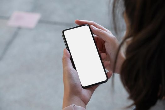 Top view woman holding blank screen mock up mobile phone, close up shot.
