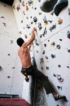 young and fit man exercise free mountain climbing on indoor practice wall