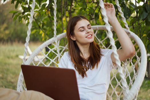 cheerful woman outdoors in hammock with laptop rest. High quality photo