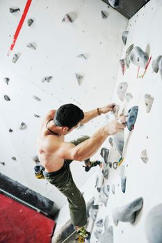 young and fit man exercise free mountain climbing on indoor practice wall