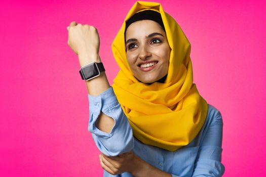 muslim woman with smart watch technology posing pink background. High quality photo
