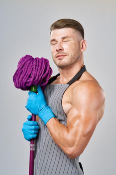 Muscled man in apron with mop posing cleaning. High quality photo