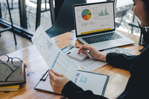Business woman using calculator for analysis maketing plan, Accountant calculate financial report, computer with graph chart. Business, Finance and Accounting concept.