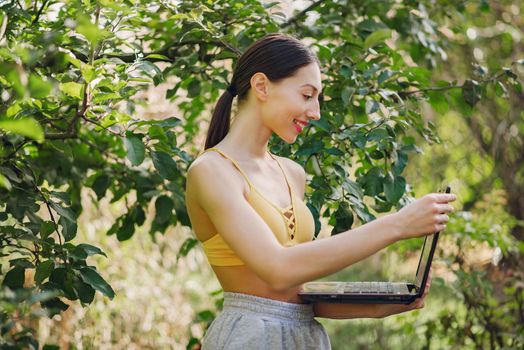 Girl in a summer park. Woman in a yellow top. Lady with a laptop.