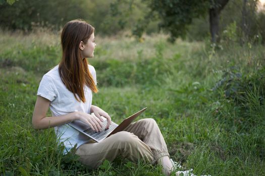 women outdoors in field with laptop leisure technology freedom. High quality photo