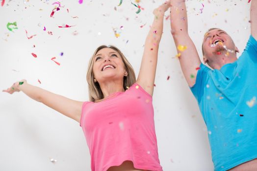 happy young romantic  couple in love  celebrating and blowing confetti decorations at new year and charismas  party