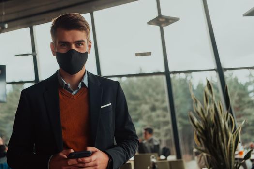 corporate businessman wearing a protective medical face mask at modern open space office concept of new normal in business