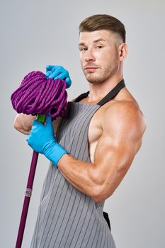 man in apron with mop in hand posing housework. High quality photo
