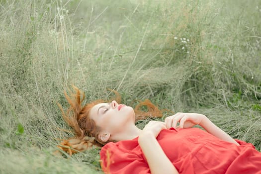 pretty woman in red dress lies on the grass in the field nature fresh air. High quality photo