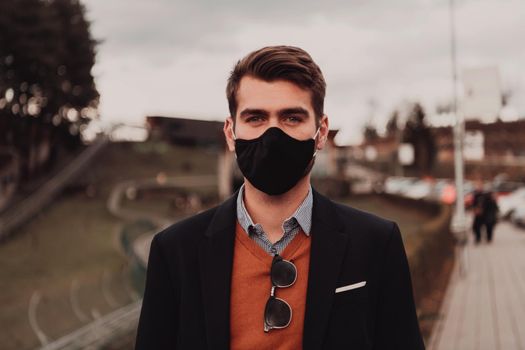 Young casual look businessman wearing a medical mask in the street urban enviroment
