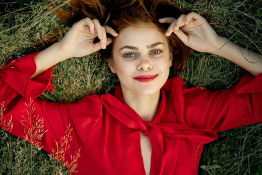 woman in red dress lies on the grass top view freedom. High quality photo