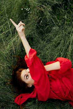 woman in red dress lies on the grass fresh air nature freedom. High quality photo