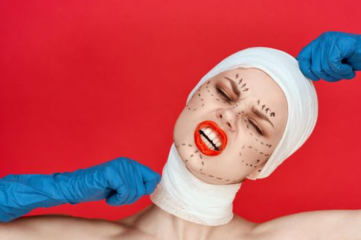 portrait of a woman in blue gloves syringe in hands contour on the face lifting red background. High quality photo