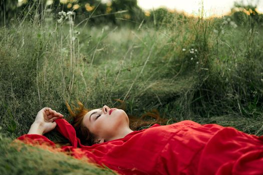 woman in red dress lying on the grass fresh air nature romance. High quality photo