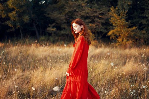 woman in a red dress in a field in nature summer landscape freedom. High quality photo