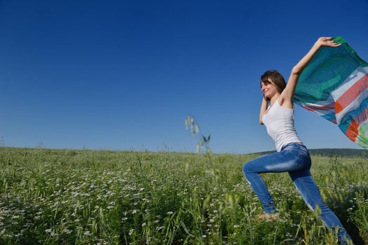 Young woman standing jumping and running  on a wheat field with blue sky in  background at summer day representing healthy life and agriculture concept