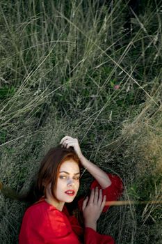 pretty woman in red dress lies on the grass posing top view. High quality photo