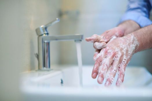 Coronavirus infection and spreading prevention, proper Washing hands with liquid soap. Hygiene male antibacterial hands water wash closeup in bathroom.