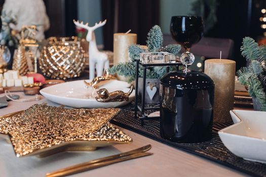 Photo of Christmas table decoration with festive dinnerware with candles. New Year eve concept