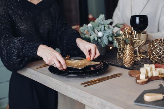 Cropped photo of woman tasting cheese on a wooden board with Christmas decorations in the background