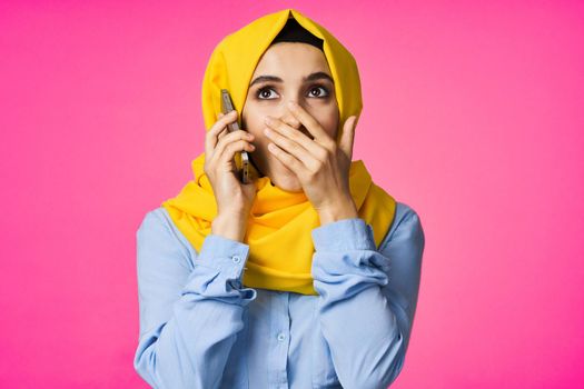 Muslim woman wearing hijab telephone communication technology pink background. High quality photo