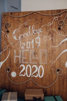 Wooden background with painted white numbers 2020 and word HELLO from above. Top view of upcoming New Year numbers with rope and pine cones.