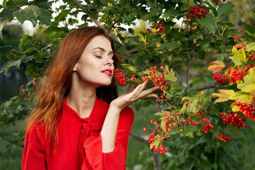 woman in red shirt near bush berries nature summer. High quality photo