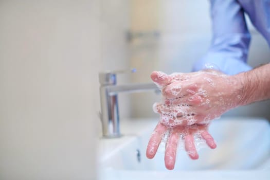 Coronavirus infection and spreading prevention, proper Washing hands with liquid soap. Hygiene male antibacterial hands water wash closeup in bathroom.