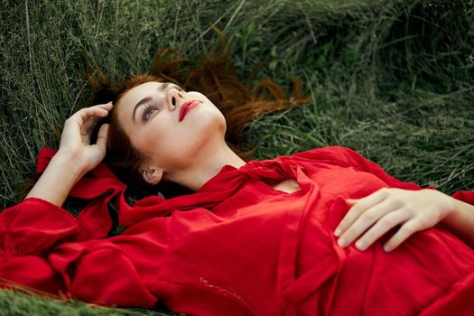 woman in red dress lies on the grass address fashion summer. High quality photo