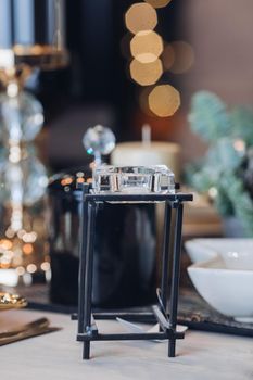 Close up of high glass candlestick on table near Christmas decoration. New Year eve concept