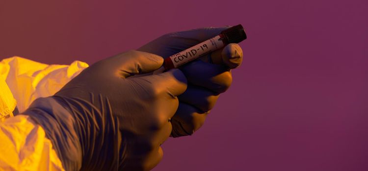 Coronavirus, Doctor holding positive covid-19 virus Blood Sample test tube. Wearing biohazard epidemic Protective mask, suit and glows neon light background