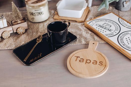 Top view of black coffee mug near wooden cutting board for cheese. Copy space