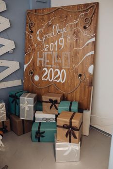 Wooden background with painted white numbers 2020 and word HELLO from above. Top view of upcoming New Year numbers with rope and pine cones.