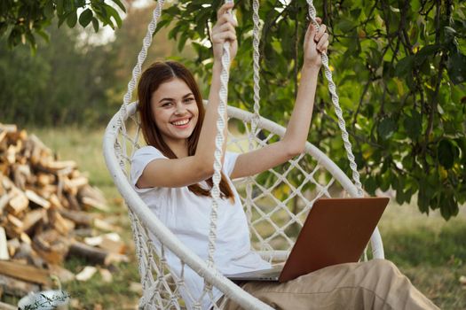 woman with laptop outdoors resting in hammock internet. High quality photo