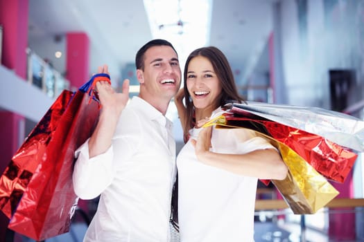 happy young couple with bags in shopping centre mall